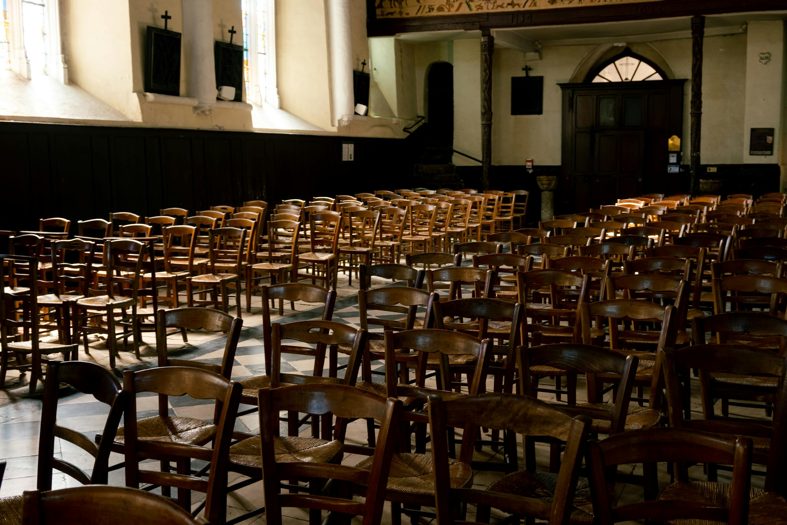 A serene church interior in France featuring rows of wooden chairs illuminated by warm sunlight through the windows.